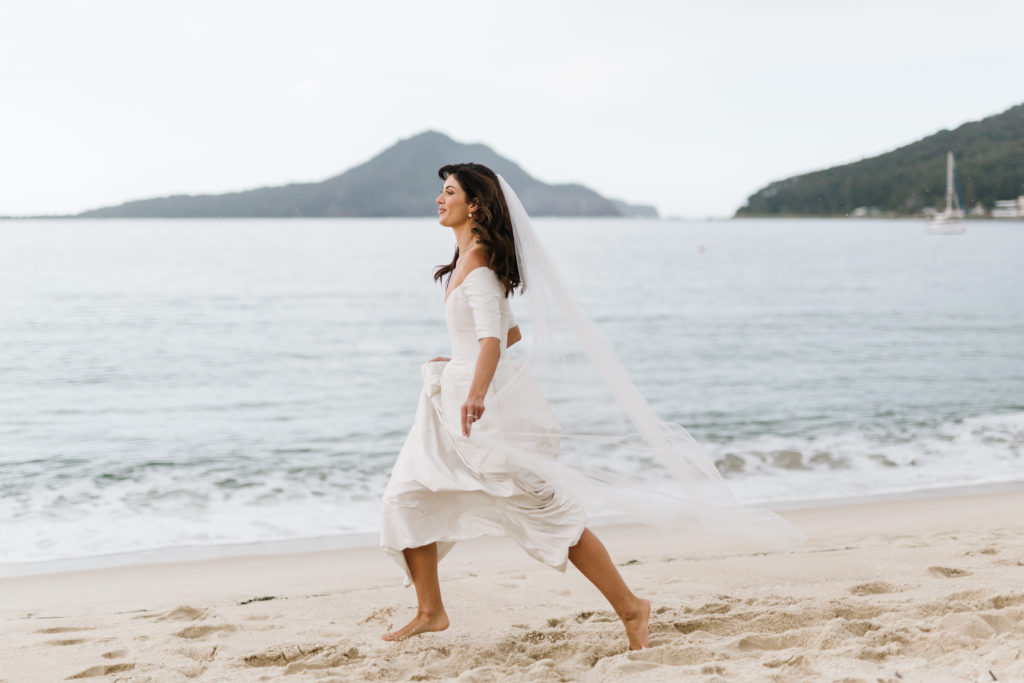 Bride running along the beach Shoal Bay Beach Elopement 