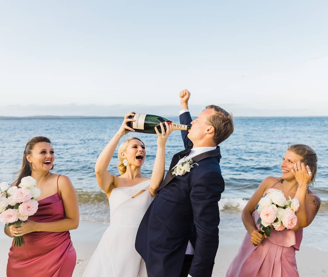 groom chugging wine as the bride holds up the wine bottle
