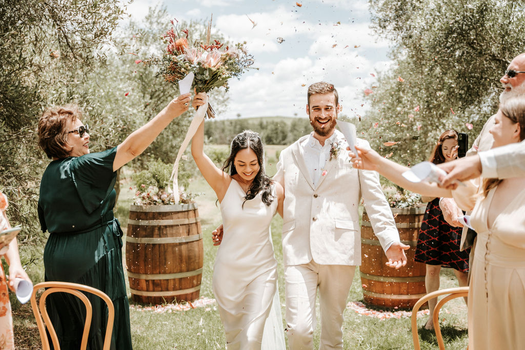 couple walk back down the aisle while getting showered in eco-confetti at Whispering Brook Elopement