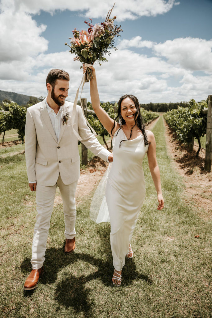 Couple walks through the vineyard at Whispering Brook in wedding clothes