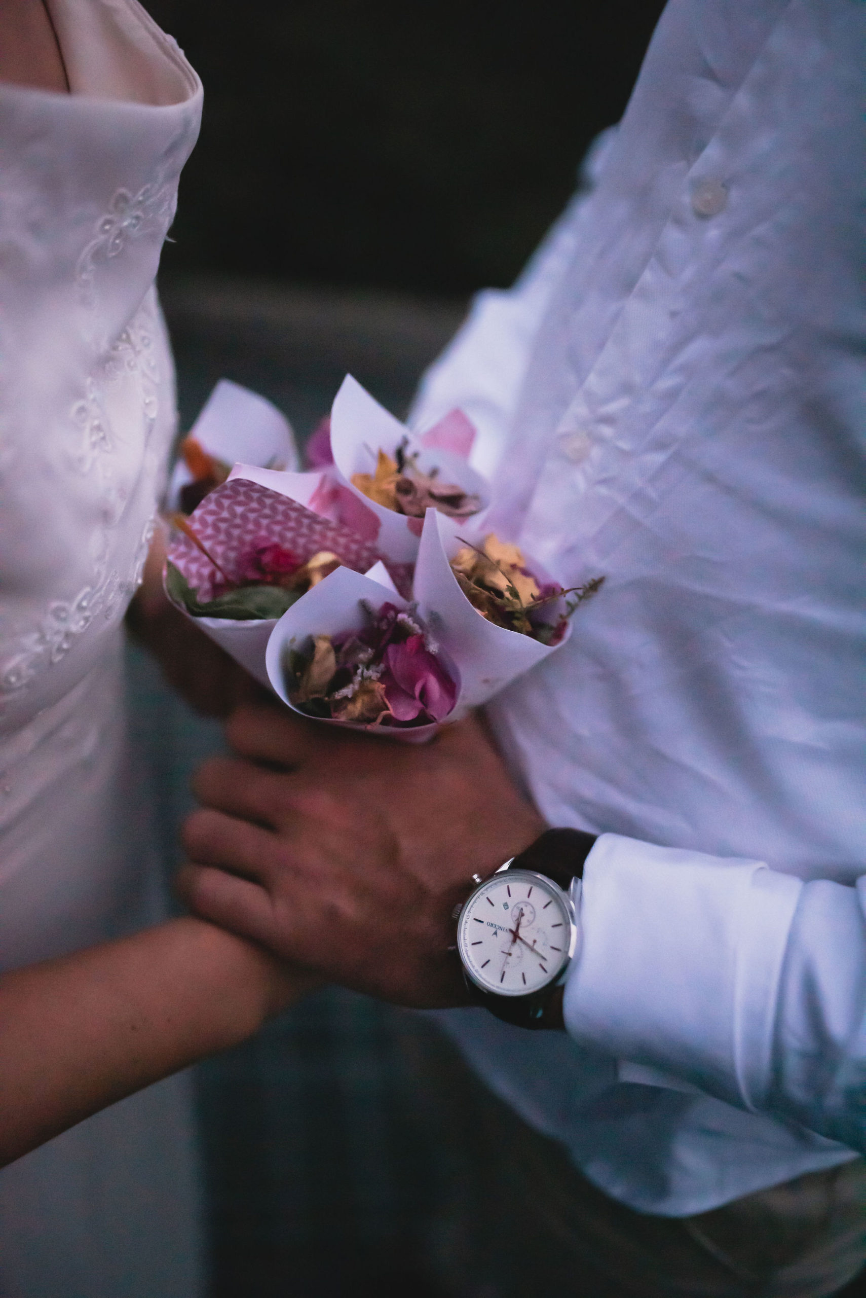 close-up shot of bride and groom's hands holding cones of eco-confetti