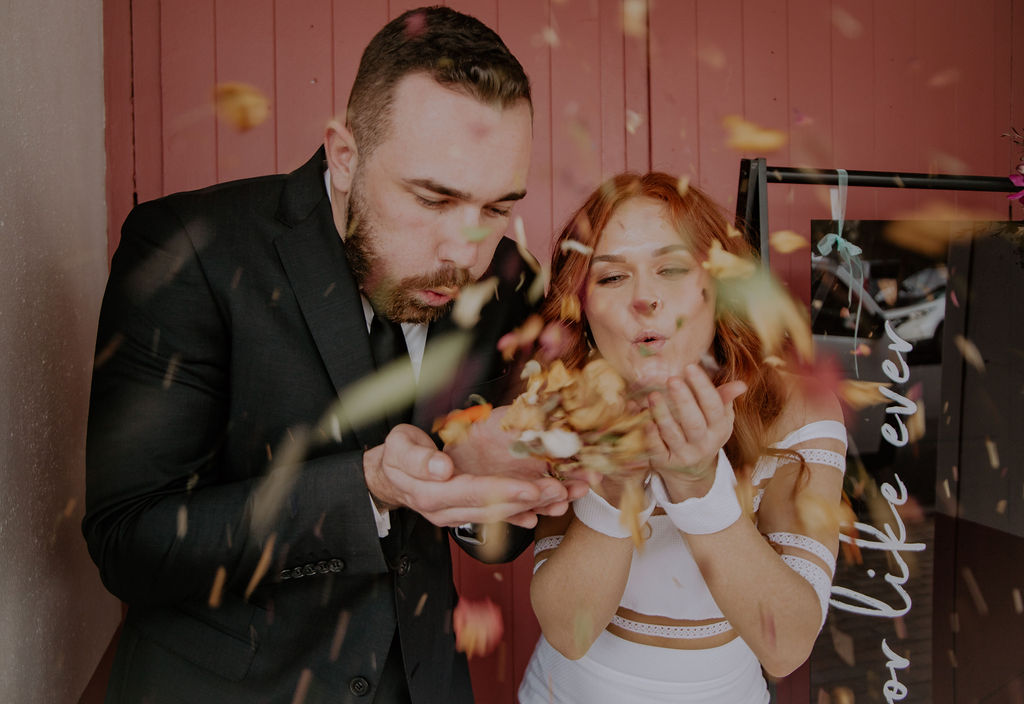 Couple blowing eco-confetti at disco inspired wedding
