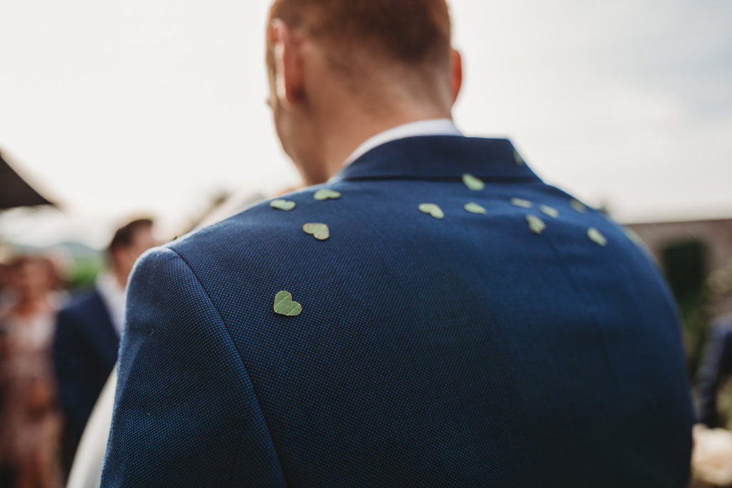 Groom has heart shaped confetti on his suit jacket. 