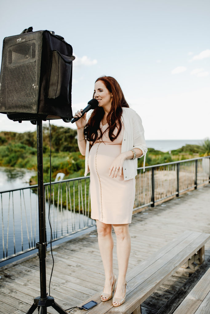 Pregnant Julie Muir testing her PA system while standing on a bench at Caves Beach Boardwalk