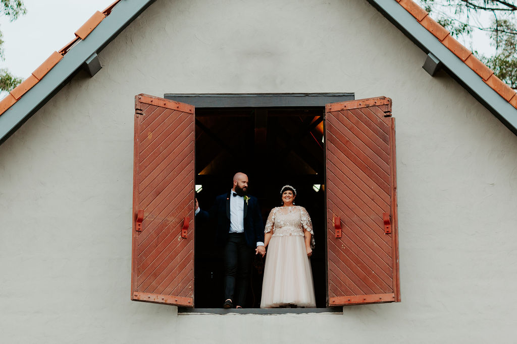 Newlyweds arguing at an open barn door up high on the edge.