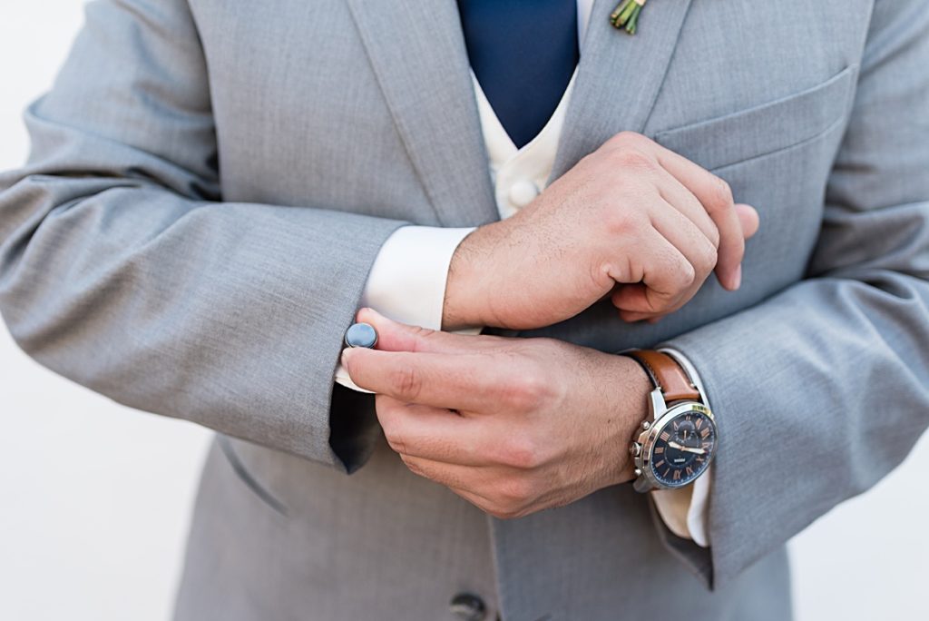 close up of groom putting on a cufflink