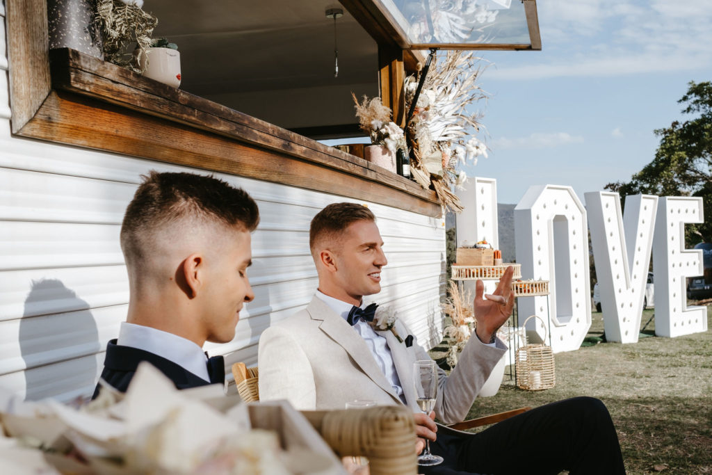 Grooms enjoying champagne while sitting down at Adams Peak wedding inspiration styled shoot