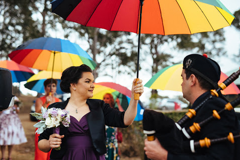 Bride handing a rainbow umbrella to bag piper at Block Eight Winery wedding
