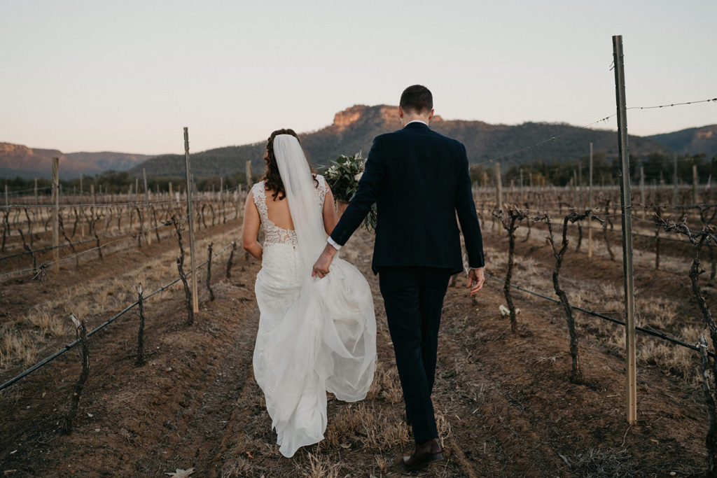 Hunter Valley Wedding Venue Margan Wines and Restaurant bride and groom walking through a bare vineyard