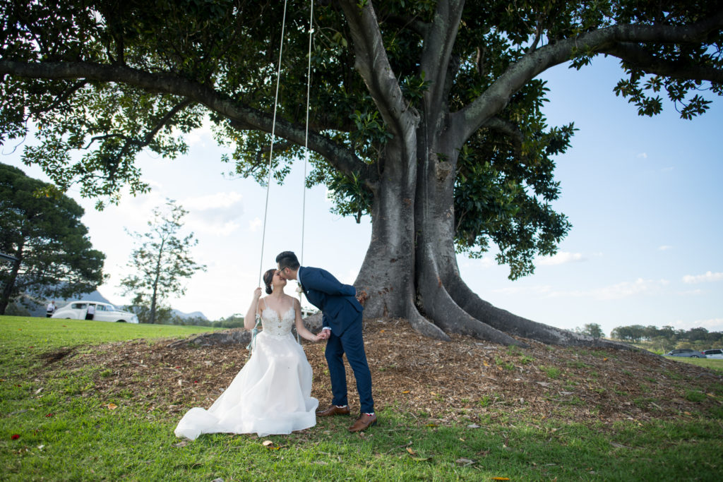 bride sitting on a swing and kissing groom at a Hunter Valley Wedding Venue in Ben Ean
