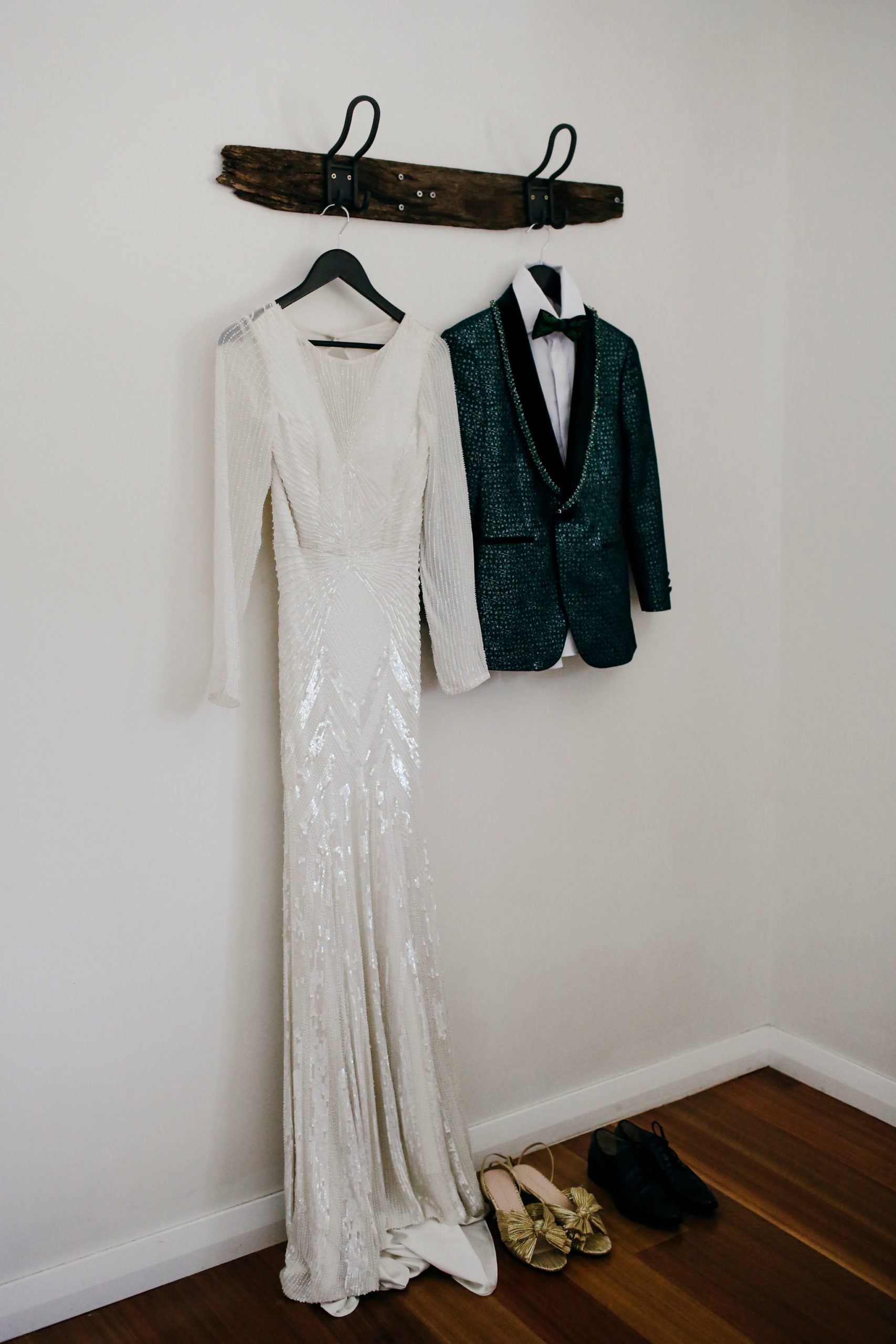 Bride's dress and other bride's green suit jacket hanging on teh wall of the bedroom at Adam's Peak.