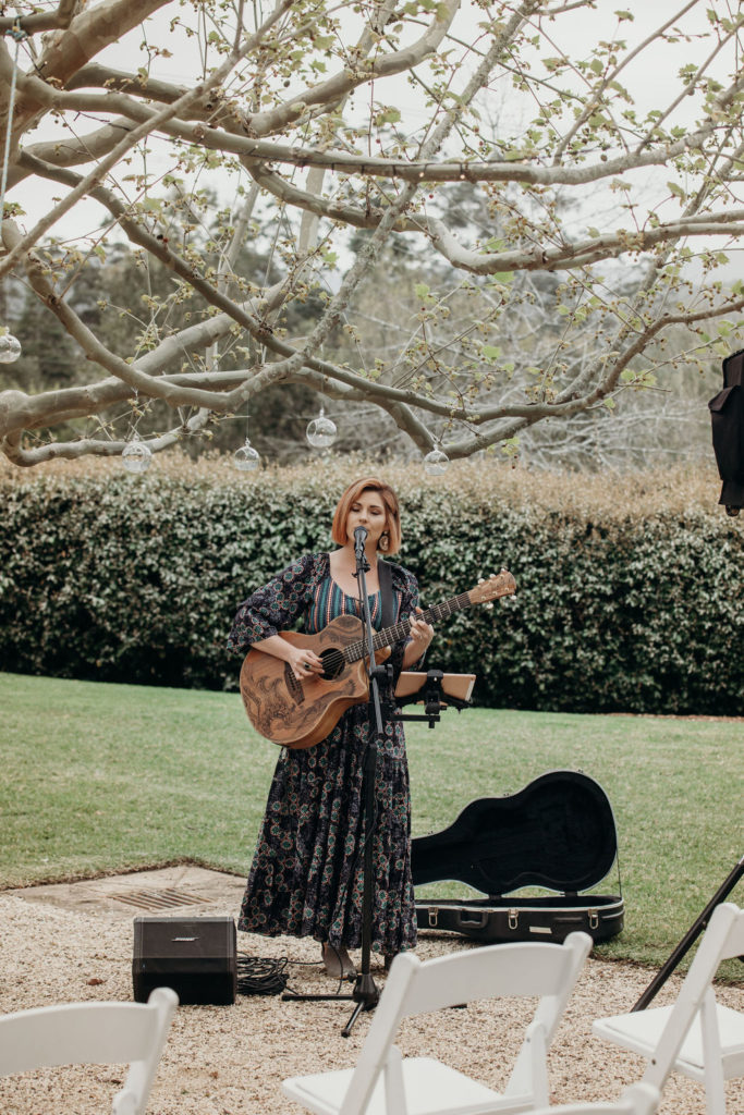 Wedding musician singing with her guitar at Fernbank Farm
