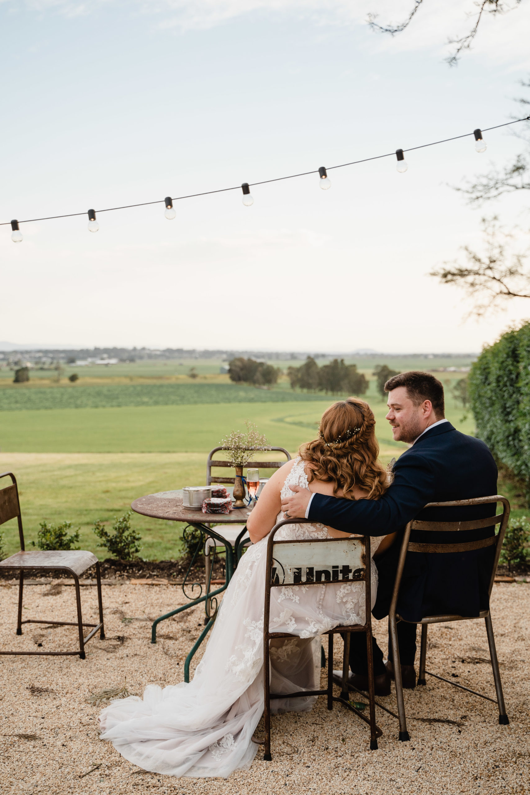 Bride and groom sitting and gazing out at the field at Wallalong House