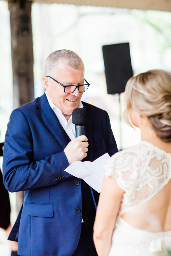 Groom with glasses reading his vows to his wife during Stonehurst Cedar Creek Wedding