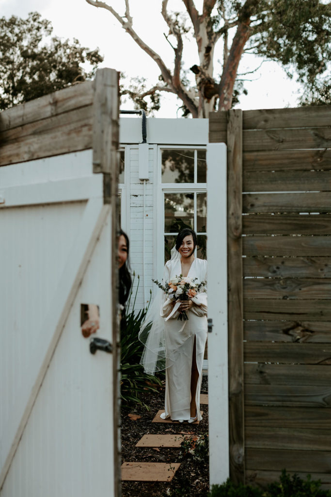 Open wooden door showing bride standing with bouquet at Vinden Wines
