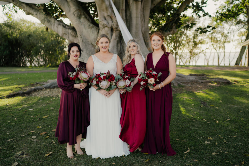 Bride and her three bridesmaids in mismatched purple and wine bridesmaid dresses at Stanley Park