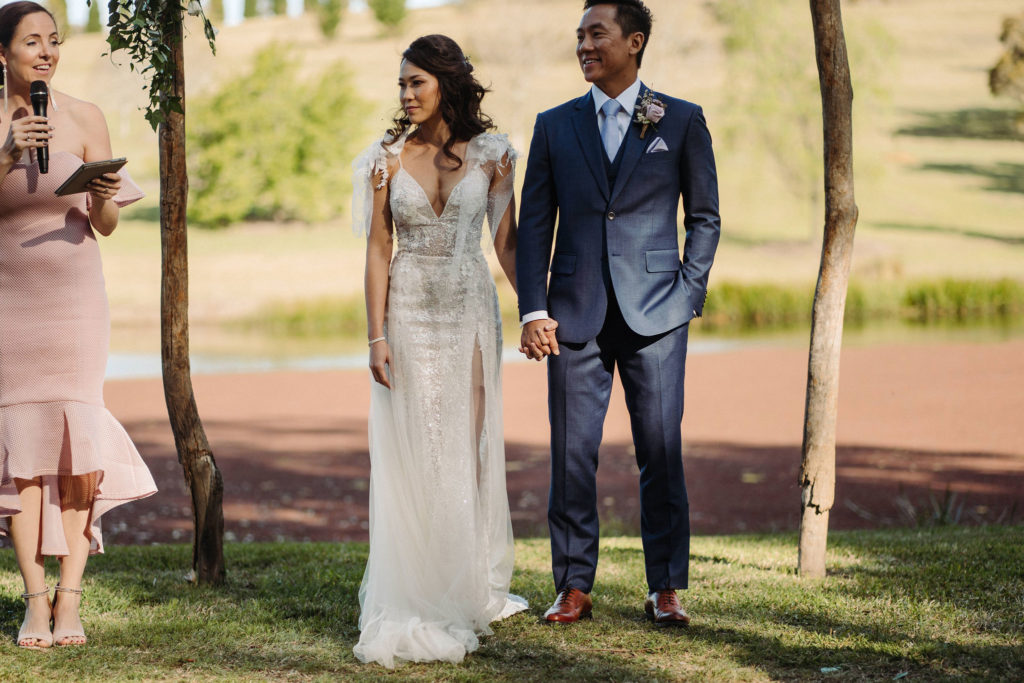 Couple holding hands mid ceremony at The Woodhouse Wollombi