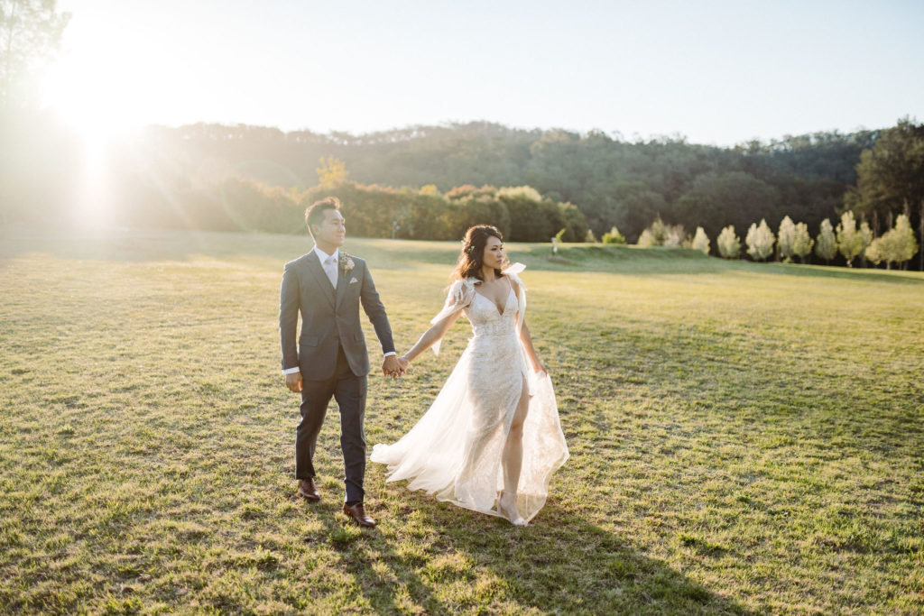 Groom and bride walking in a field at The Woodhouse Wollombi wedding