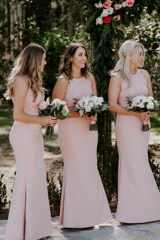 Three bridesmaids in long pink dresses holding bouquets at Circa 1876 