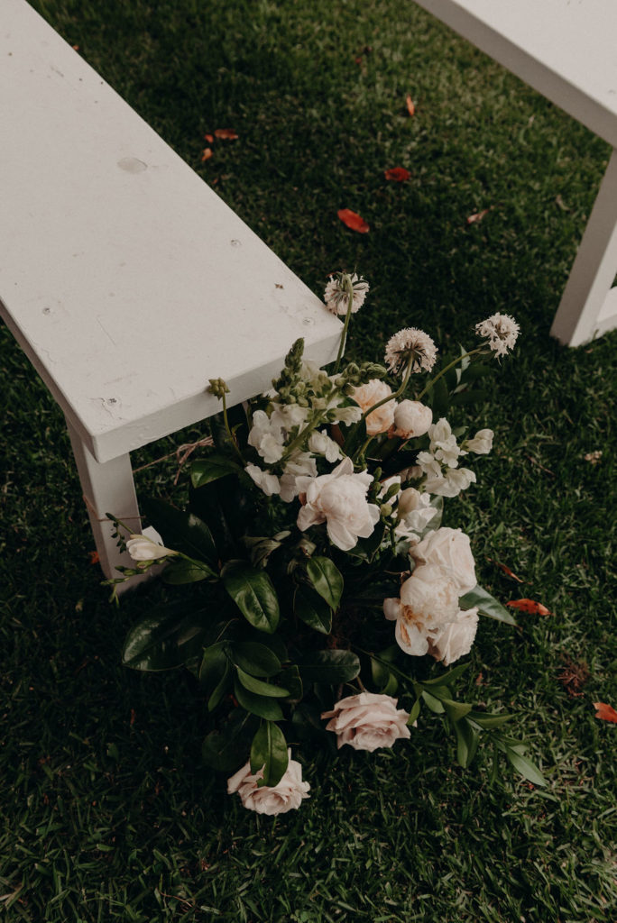 Flower arrangement beside white wooden bench at Mindaribba House wedding
