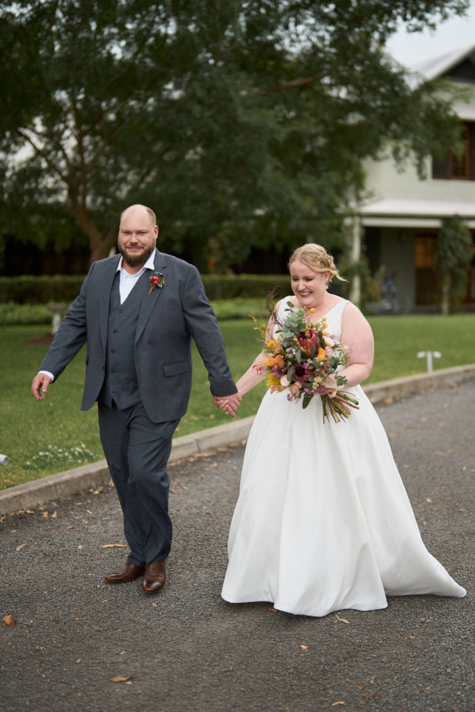 Bride and groom walking on a paved path in Spicers Vineyard Estate