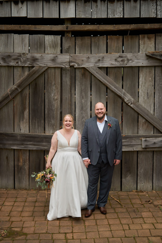 Bride and groom posing in front of a large barn door at Spicers Vineyard Estate
