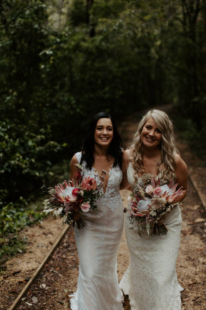 Brides smiling and posing in the middle of an old train track