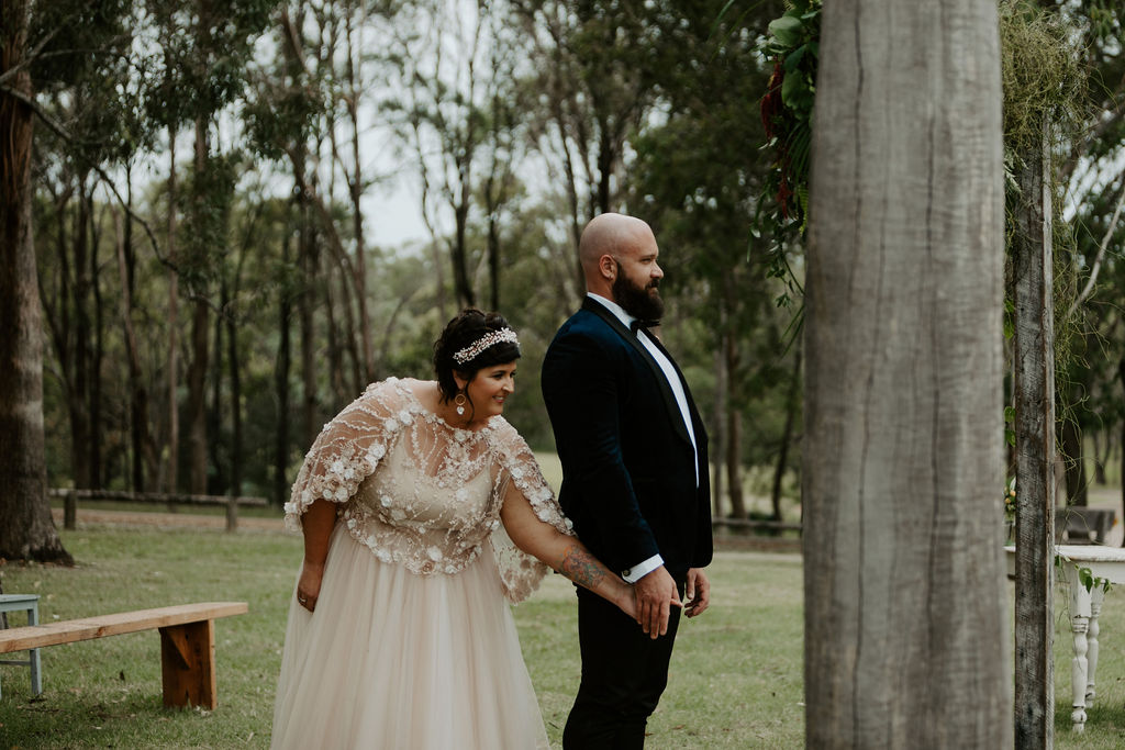 Bride reaching and holding groom's hand from behind at Wandin Valley wedding