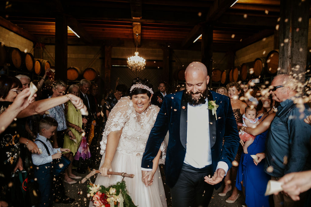 Bride and groom walking down the aisle while showered in petals at Wandin Valley wedding