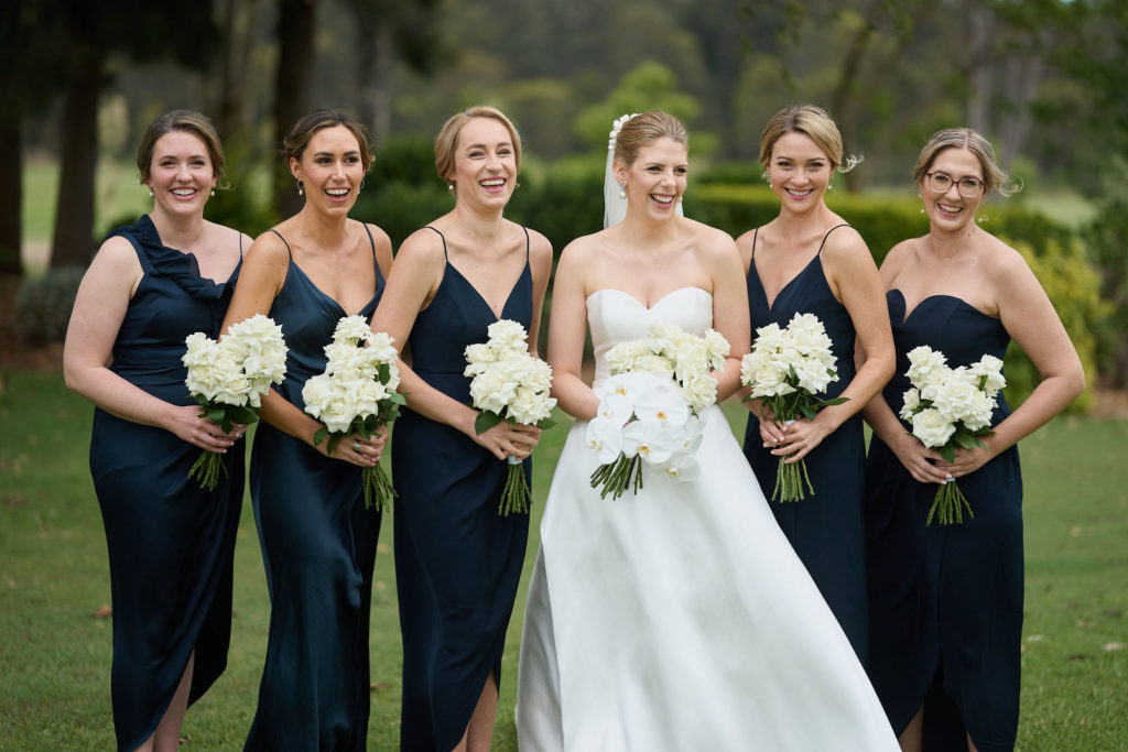 Bride and her bridesmaid with their bouquets laughing together 