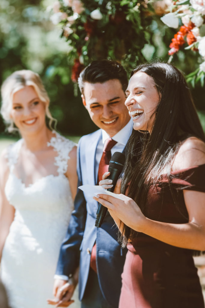 Bride and groom laughing with their friend who was reading a letter to them