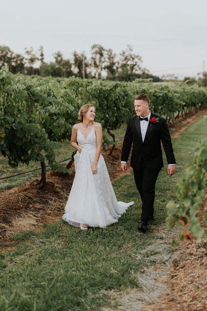 Newlyweds smiling at each other and walking in the vineyards at Bimbadgen Palmers Lane wedding