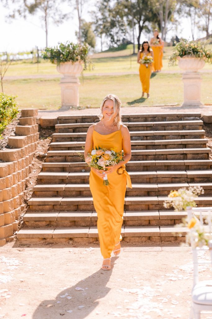 Bridesmaid in yellow dress walking down the aisle at Willow Tree Estate wedding
