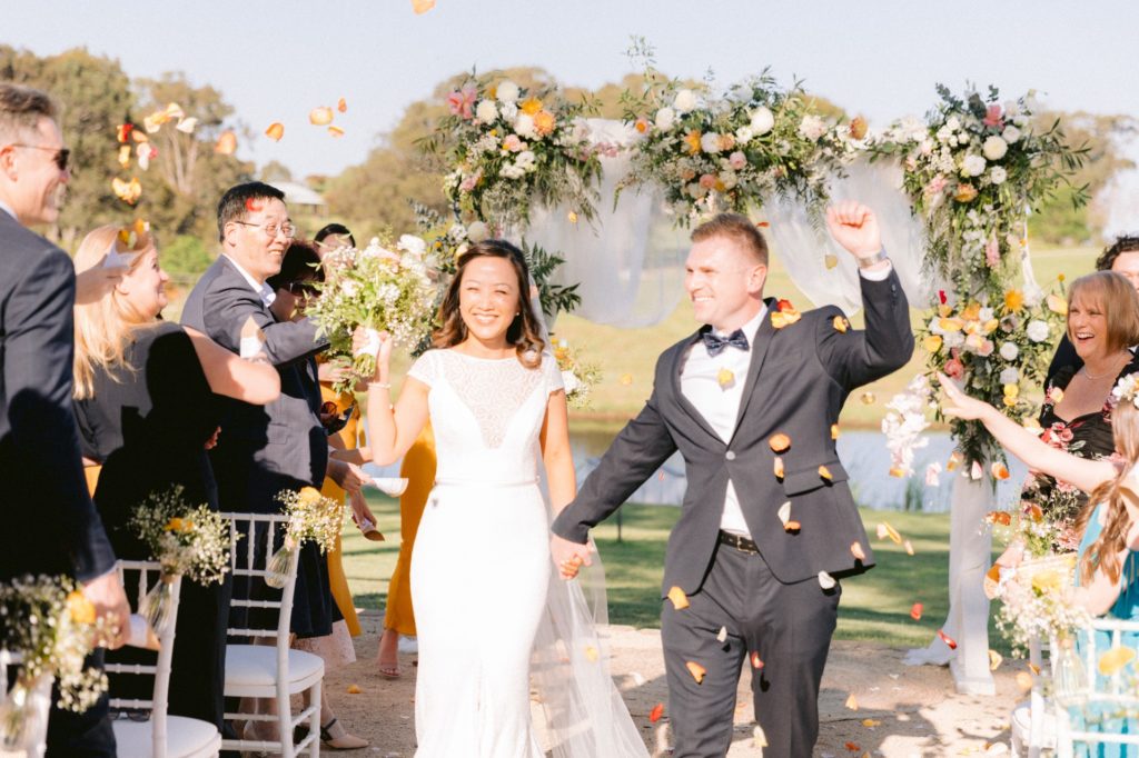 Newlyweds walking down the aisle showered in petals at Willow Tree Estate wedding