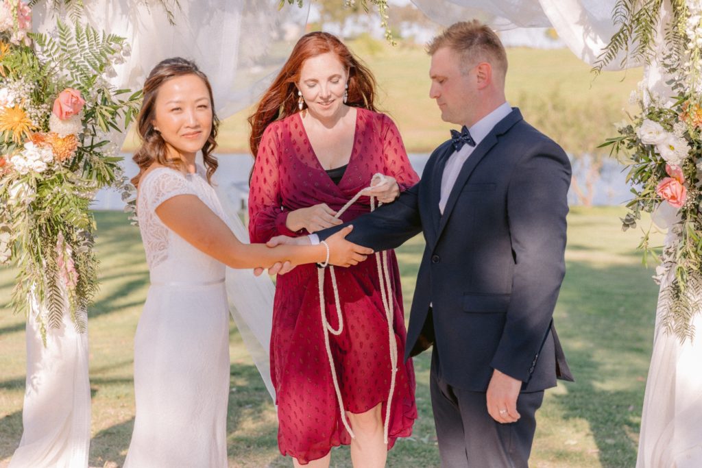 Celebrant Julie Muir using the handfasting rope with the newlyweds at Willow Tree Estate wedding