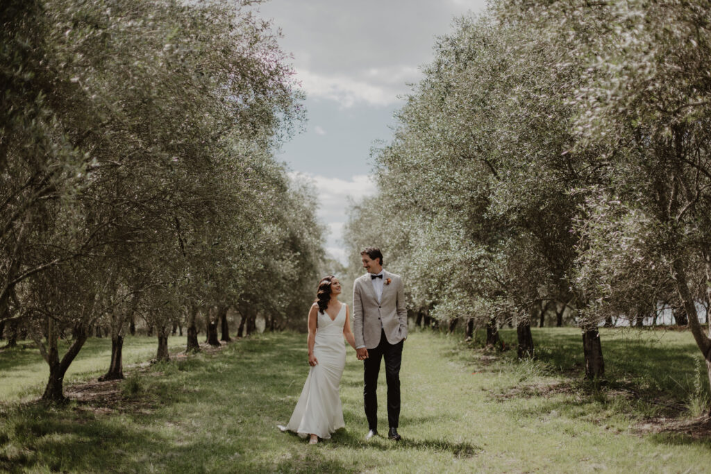 Newlywed couple walking through an orchard