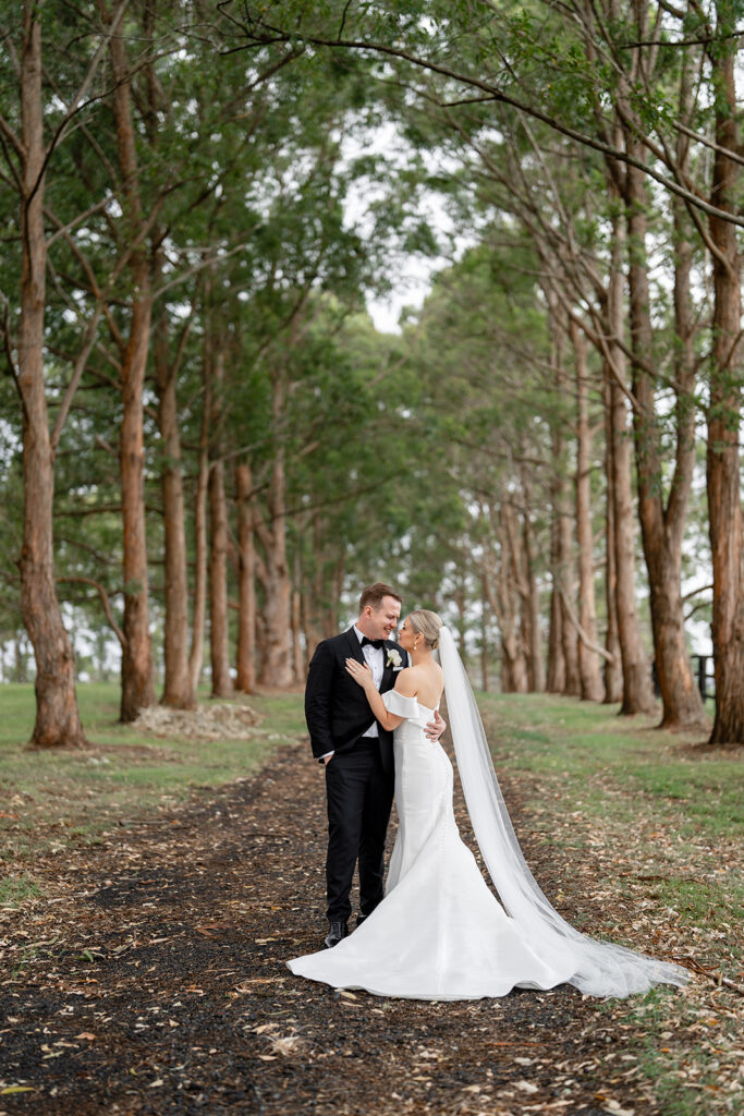 Couple embracing romantically along a tree lined path at Hunter Valley Wedding Venue Chapel Ridge