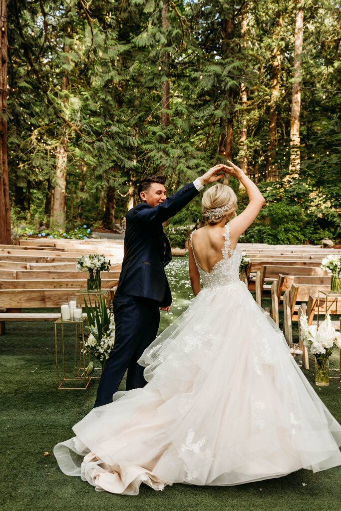 Groom twirling bride in American ceremony space in the woods