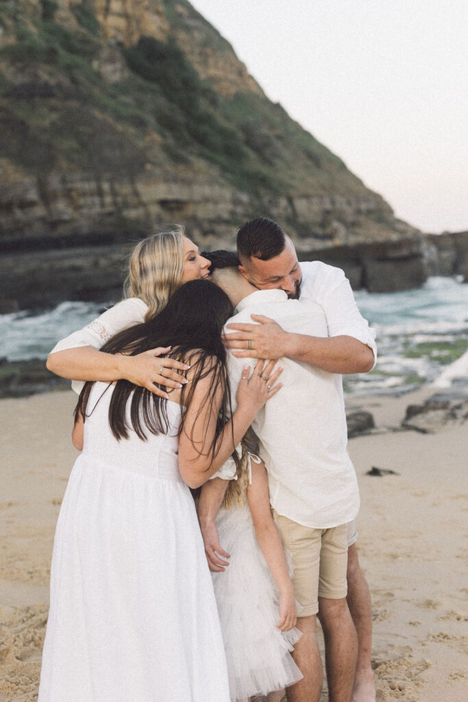 Family group hugging in a circle at Bar Beach Elopement