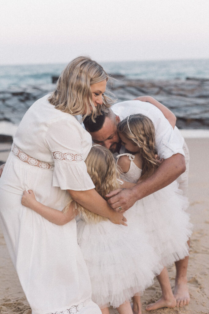 Family hugs on Bar Beach during a wedding