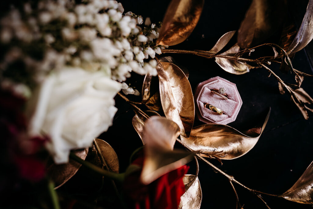 wedding rings beside flowers with golden leaves