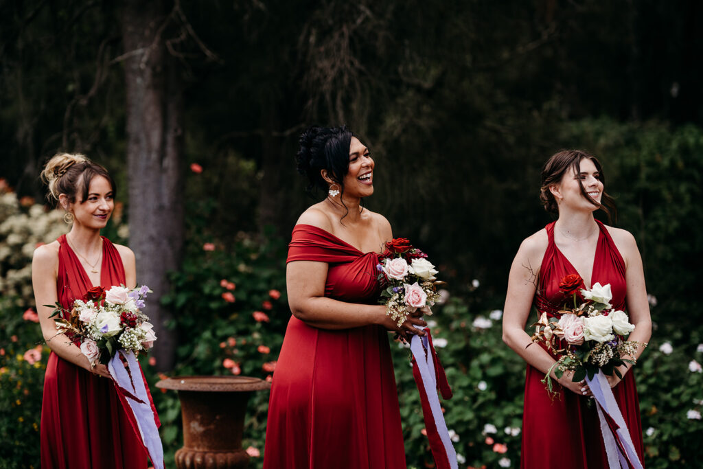 Three happy bridesmaids in red dresses and holding their bouquets at Circa 1876 wedding venue