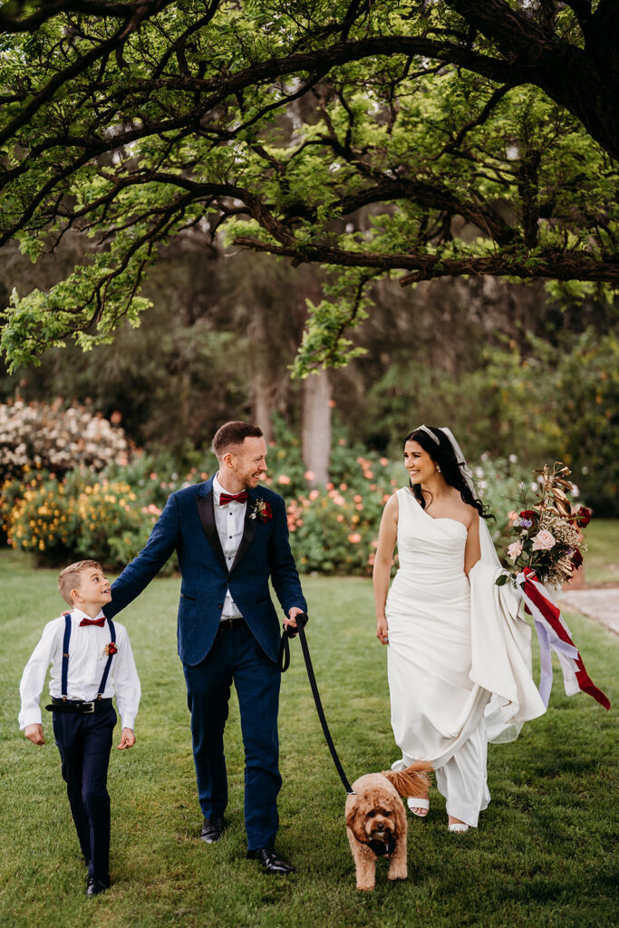 Bride and groom taking a stroll with the ring bearer and their brown dog at Circa 1876 wedding venue