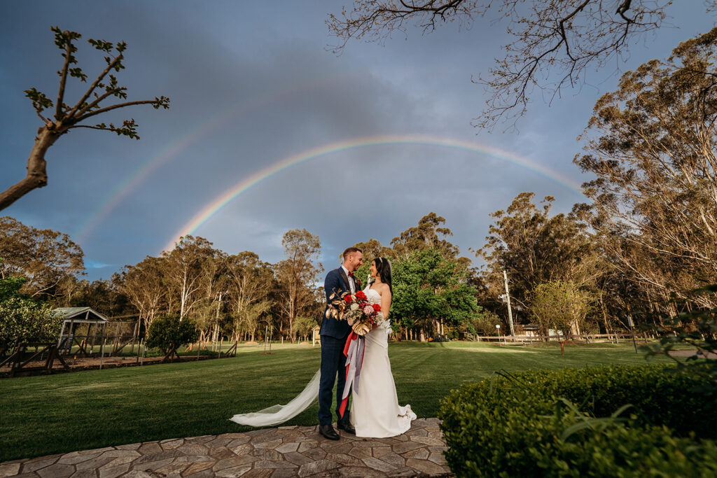 Bride and groom smiling at each other under two rainbows at Circa 1876 wedding venue