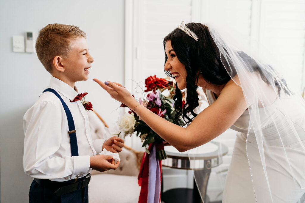Bride laughing with the ring bearer in the living room before the wedding