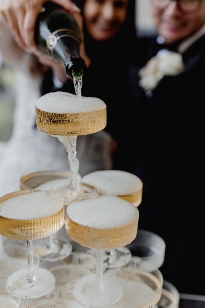 Newlyweds pouring champagne on champagne tower