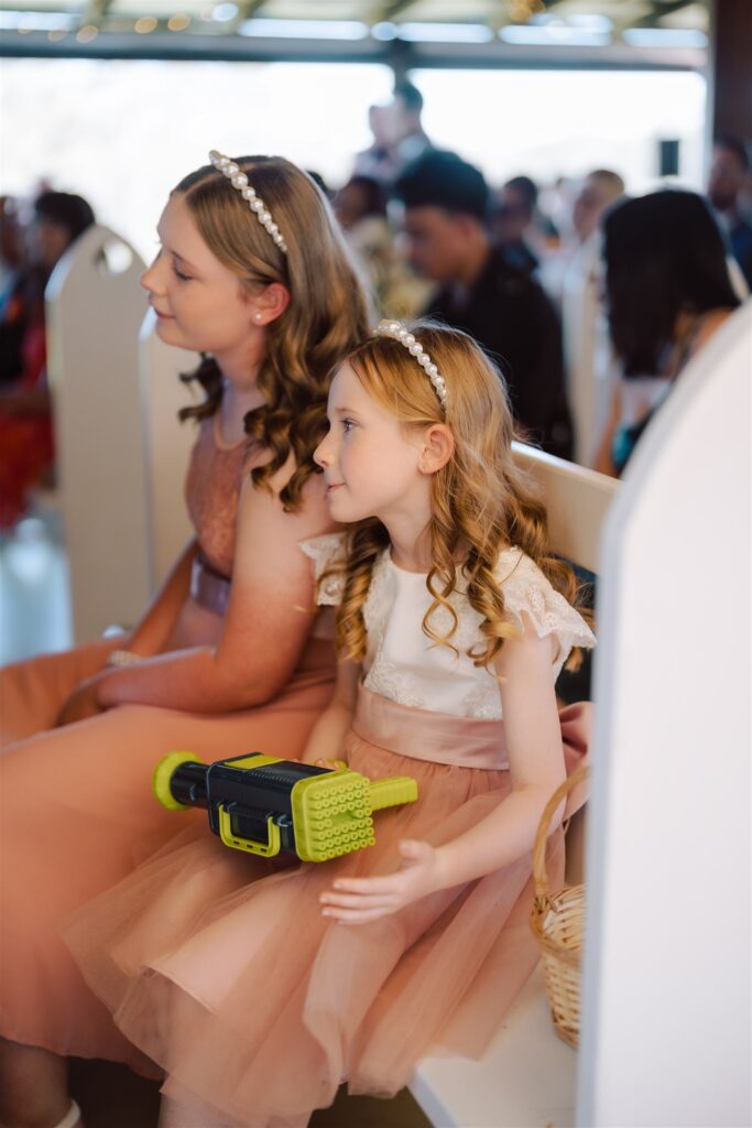 Two flower girls sitting at a wedding ceremony