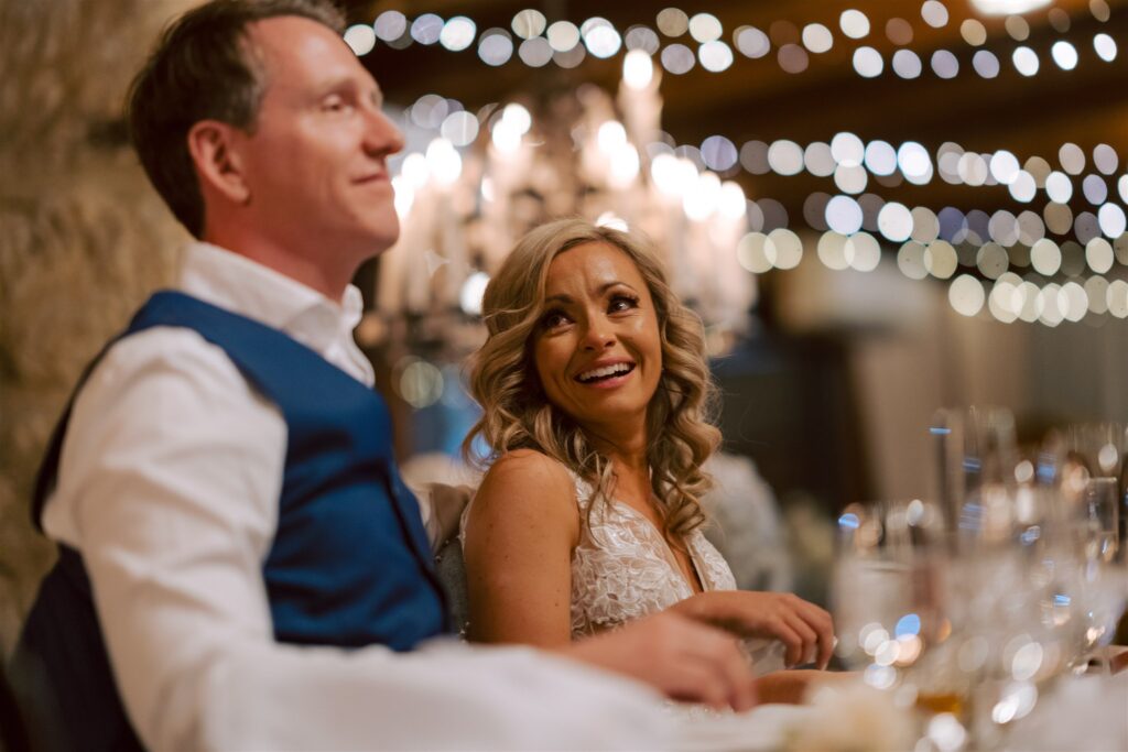 Happy bride looking at groom while they are sitting at their table during wedding reception at Peppers Creek Chapel & Barrell Room.