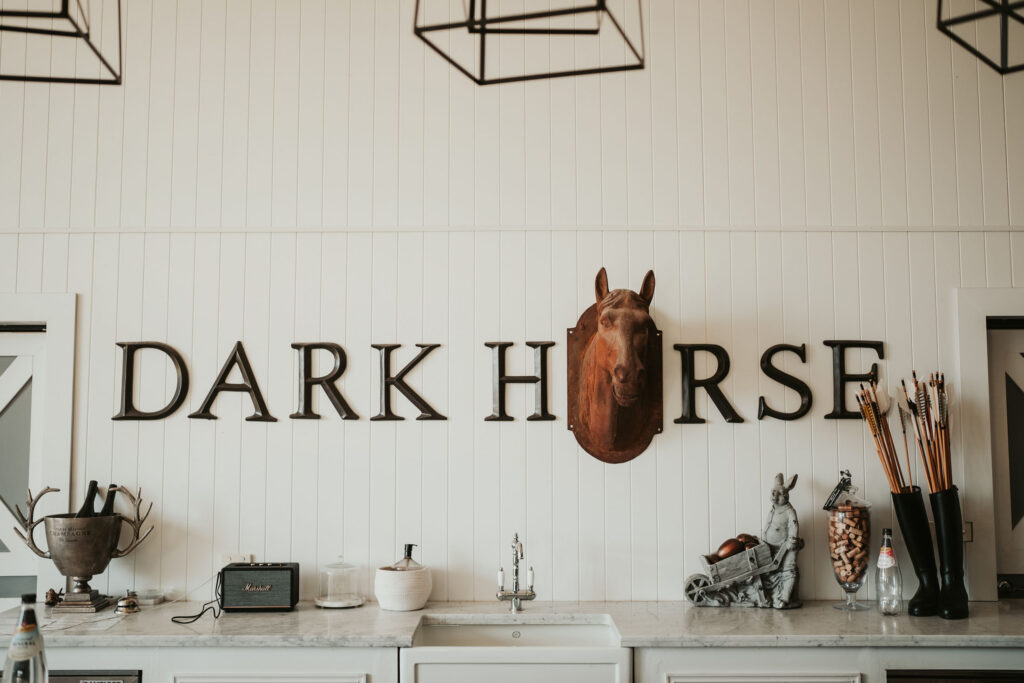 Interior wall with the name "Dark Horse" with a mounted horse head and a counter with rustic decor. 