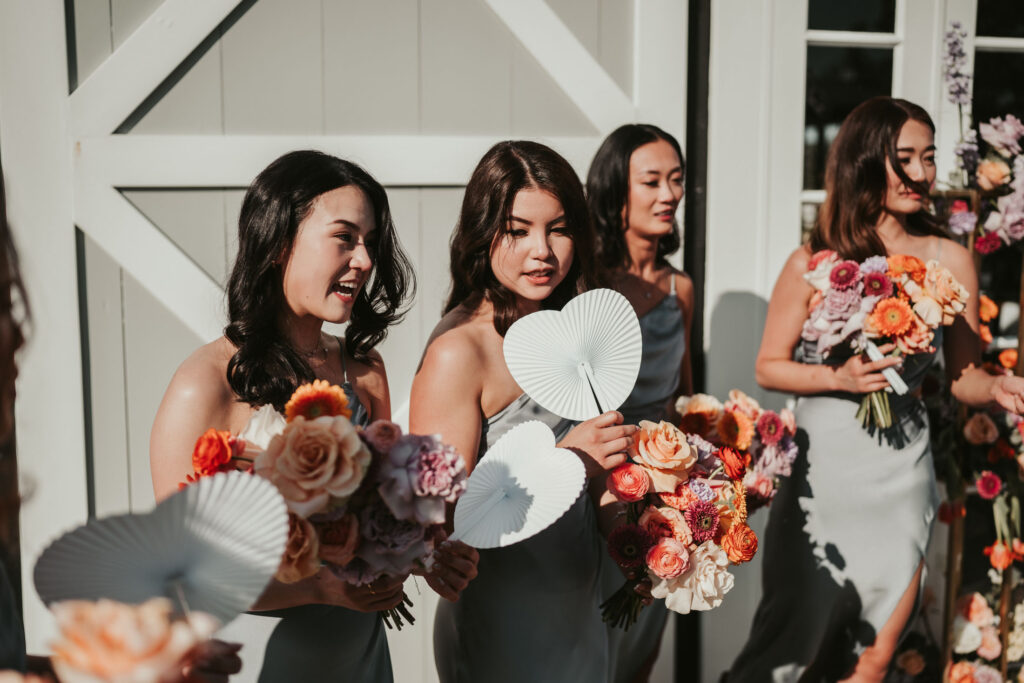 Bridesmaids in a line while carrying their bouquets and heart-shaped fans